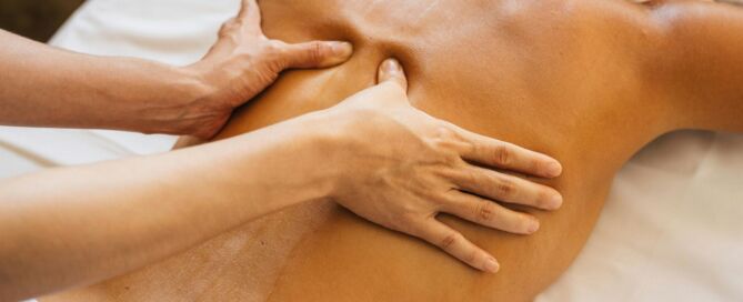 Therapeutin massiert einer Frau den Rücken